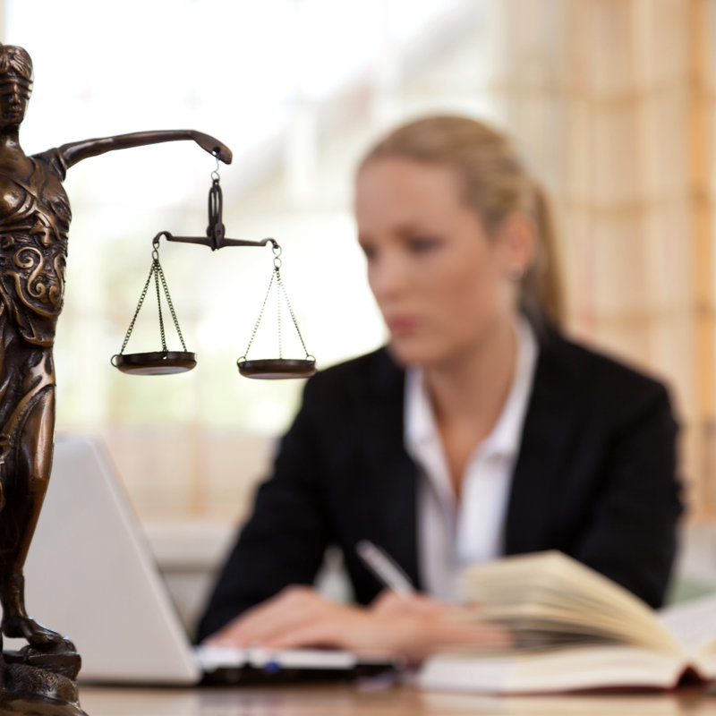 young female lawyer sitting at her desk beside a small statue of Justice