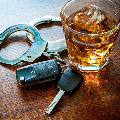 car keys next to a glass of alcohol and handcuffs